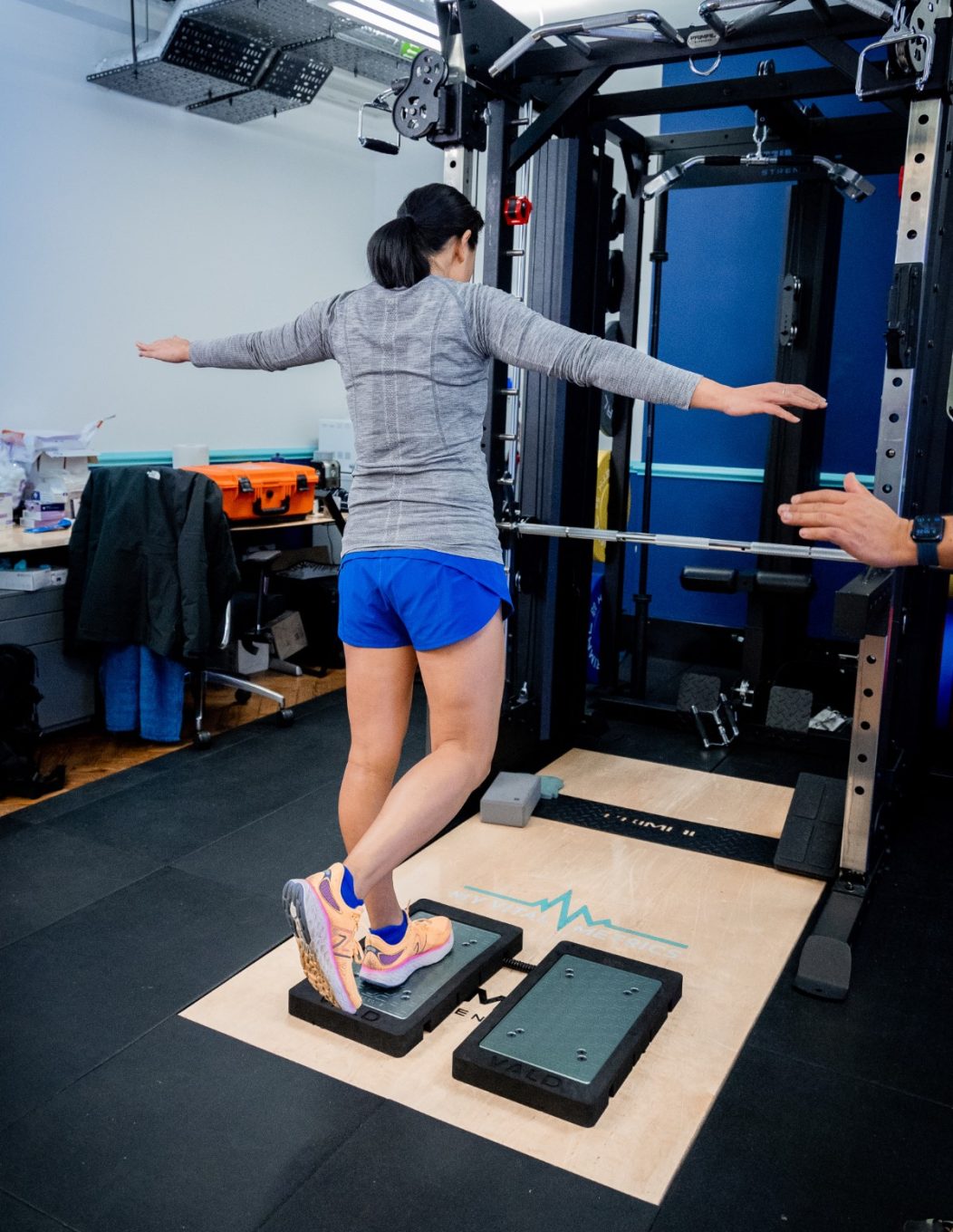 single-leg-stand The photo shows a white man having a body composition scan in a DEXA scanner. He is lying flat on his back on a raised table as the arm of the scanner passes over his body. There is a logo on the wall behind him that reads My Vital Metrics.